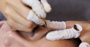 Cosmetologist applying permanent make up on woman eyebrow